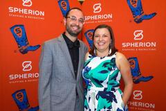 A couple standing against an orange background