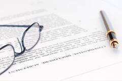 Photo of a pair of glasses and a pen resting on a legal document