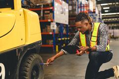 Young African American man checking a tire on a forklift
