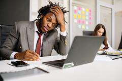 Frustrated manager sitting as desk in front of a laptop