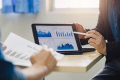 Two people examining sales statistics on a tablet
