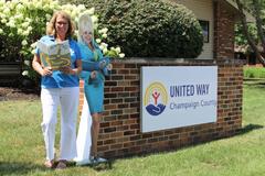 A woman holding a book next to a cutout of Dolly Parton and a sign for the United Way of Champaign County
