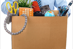 A man dressed professionally carrying a cardboard box of belongings