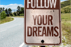A road sign that reads Follow Your Dreams