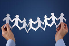 Two hands holding a paper chain cutout against a blue background