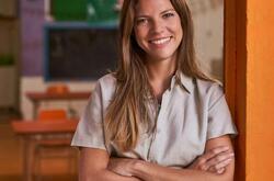 Daycare teacher smiling with arms crossed in her classroom