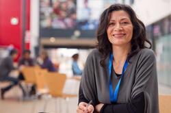 A mature woman sitting in a lounge area smiling