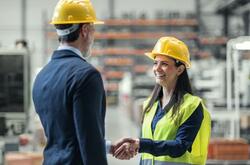 A woman shaking a man's hand and smiling in a warehouse