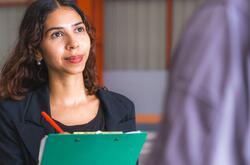 Woman holding a clipboard and interviewing a colleague