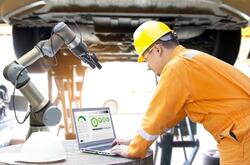 A man in a manufacturing plant using a laptop to run a machine