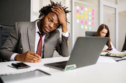 Frustrated manager sitting as desk in front of a laptop