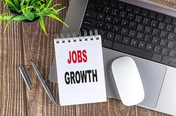 Jobs growth on notepad with laptop keyboard and mouse