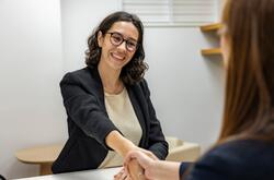 A female recruiter smiling and shaking hands with a job candidate