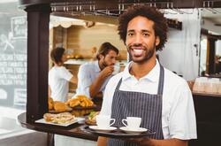 Server, young man smiling serving tray of coffee