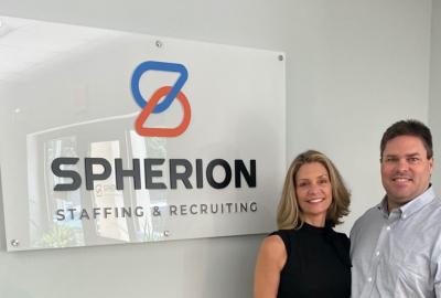 Molly & Joe Keebler of the Spherion Asheville, NC office pose in front of a Spherion logo sign