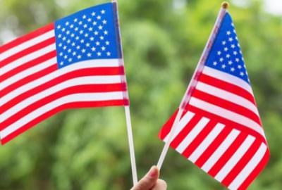 Two American flags held up against a green background