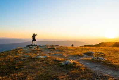 Person looking out over a mountain vista at sunrise