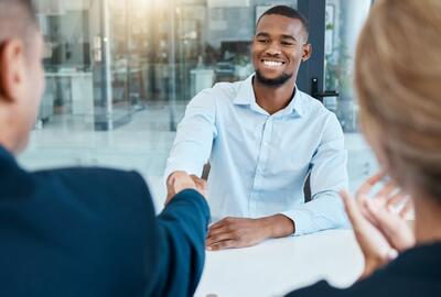 Interviewers shaking hands with a new onboarding employee