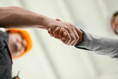 Close up of factory worker giving handshake to a engineer