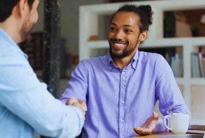Two men shaking hands and smiling in an office setting