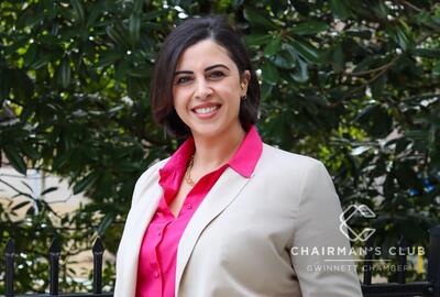 A photo of a woman in a business suit against a leafy backdrop