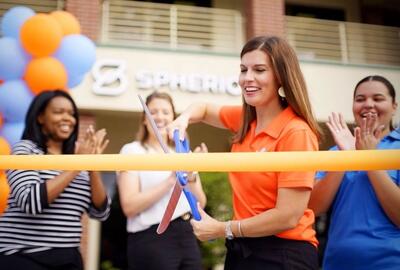 A woman cutting a ribbon at a Spherion office grand opening