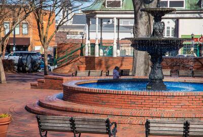 View of an outdoor brick public square with a fountain and gazebo