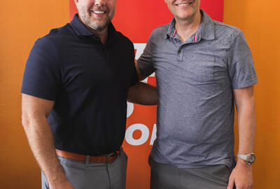 Two brothers posing in front of a Spherion sign