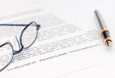 Photo of a pair of glasses and a pen resting on a legal document