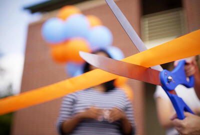Compare and Understand the Best Franchise Model for You Closeup of a hand cutting an orange ribbon with blue scissors