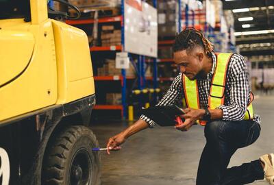 Young African American man checking a tire on a forklift
