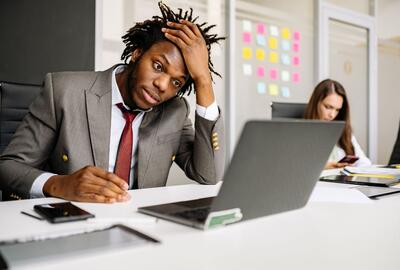 Frustrated manager sitting as desk in front of a laptop