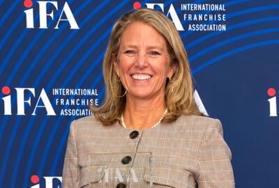 A woman smiling while holding a crystal award against a blue backdrop