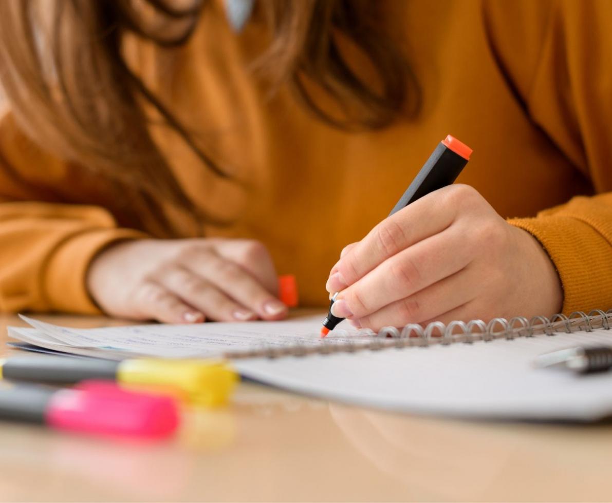 Woman writing in a notebook with highlighters