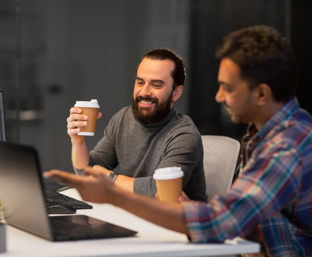 Two men talking and smiling while holding coffee cups