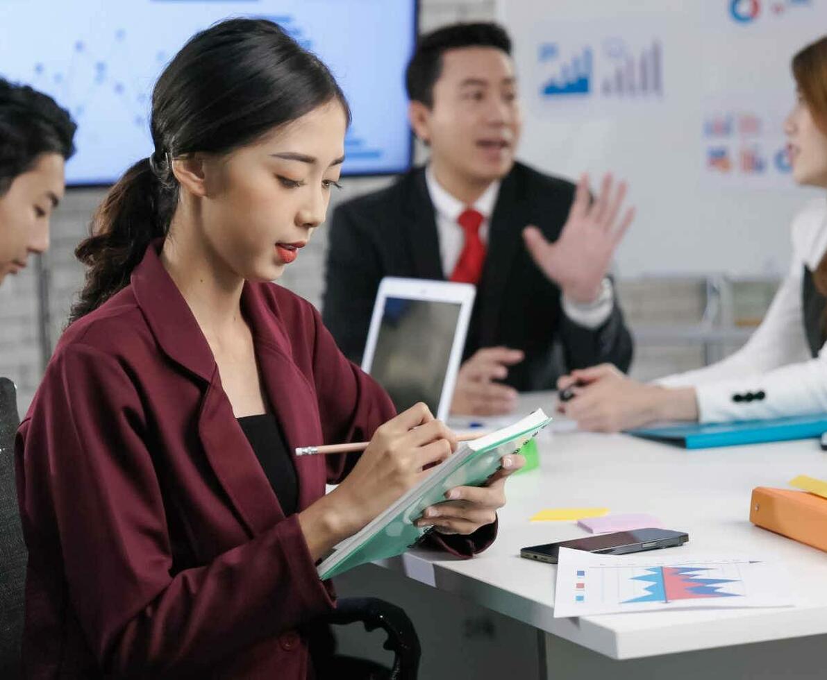 Asian_woman_working_on_a_tablet_with_her_team_in_the_background