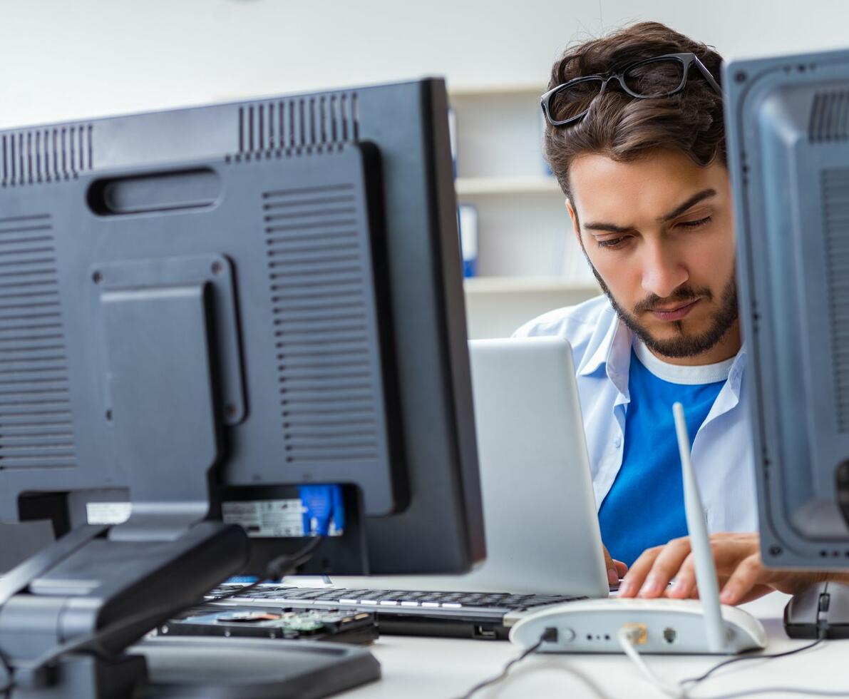 Man pictured between two computer monitors looking down at his work