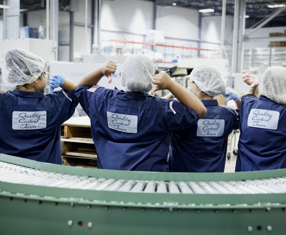 Four women on-premise workers pointing to the backs of their uniforms