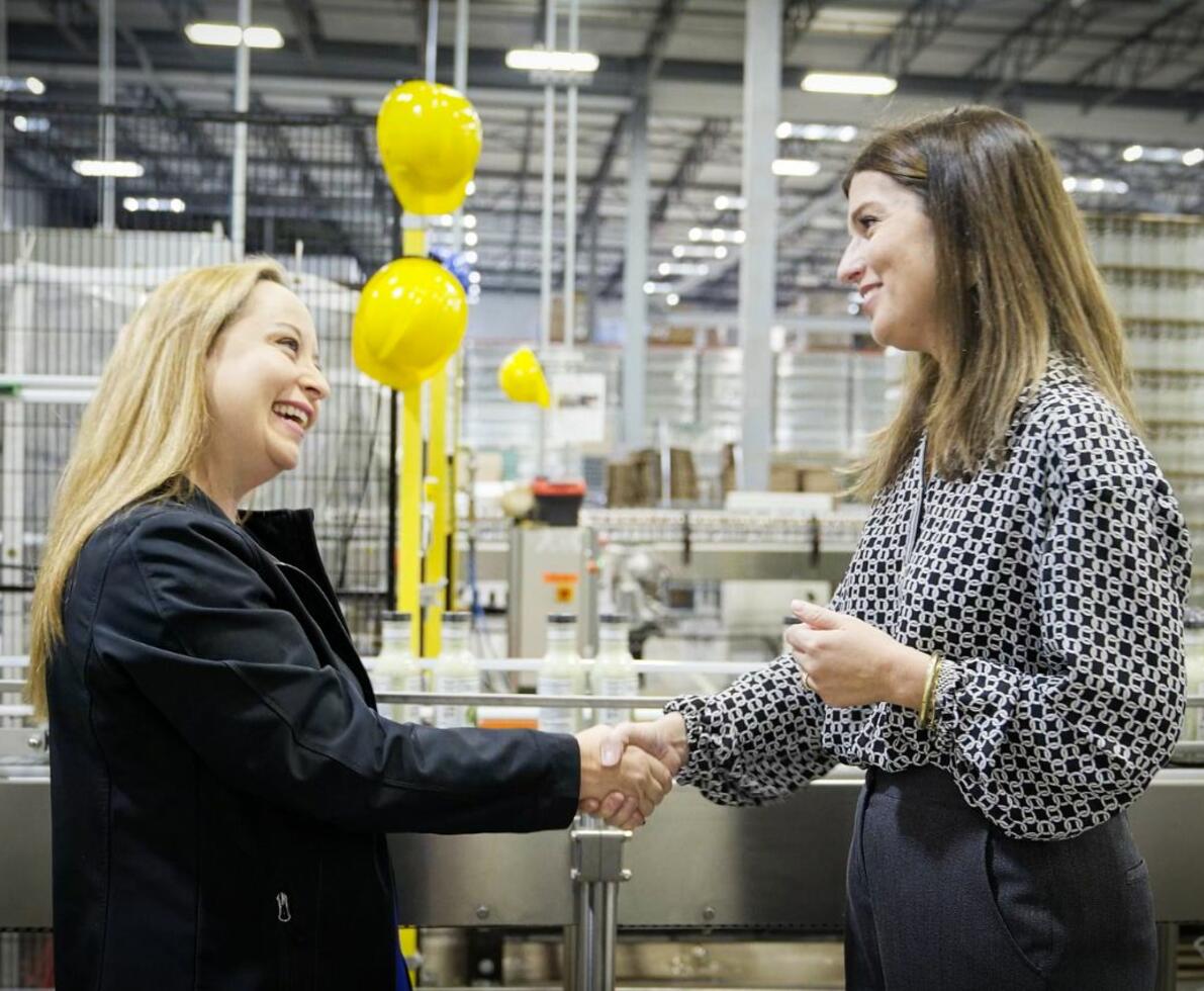 Two women shaking hands in a factory setting