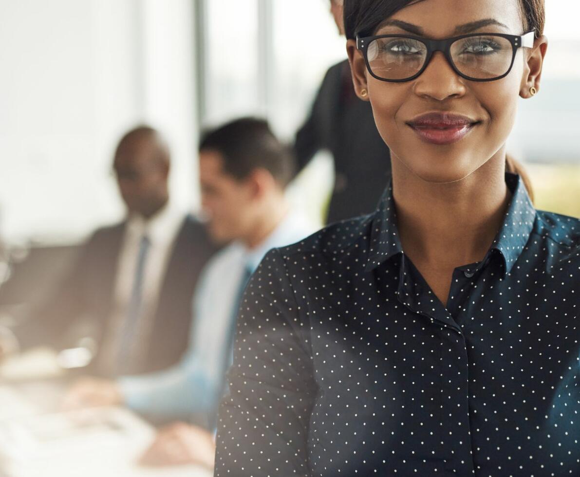 Black woman in business attire confidently smiling at camera