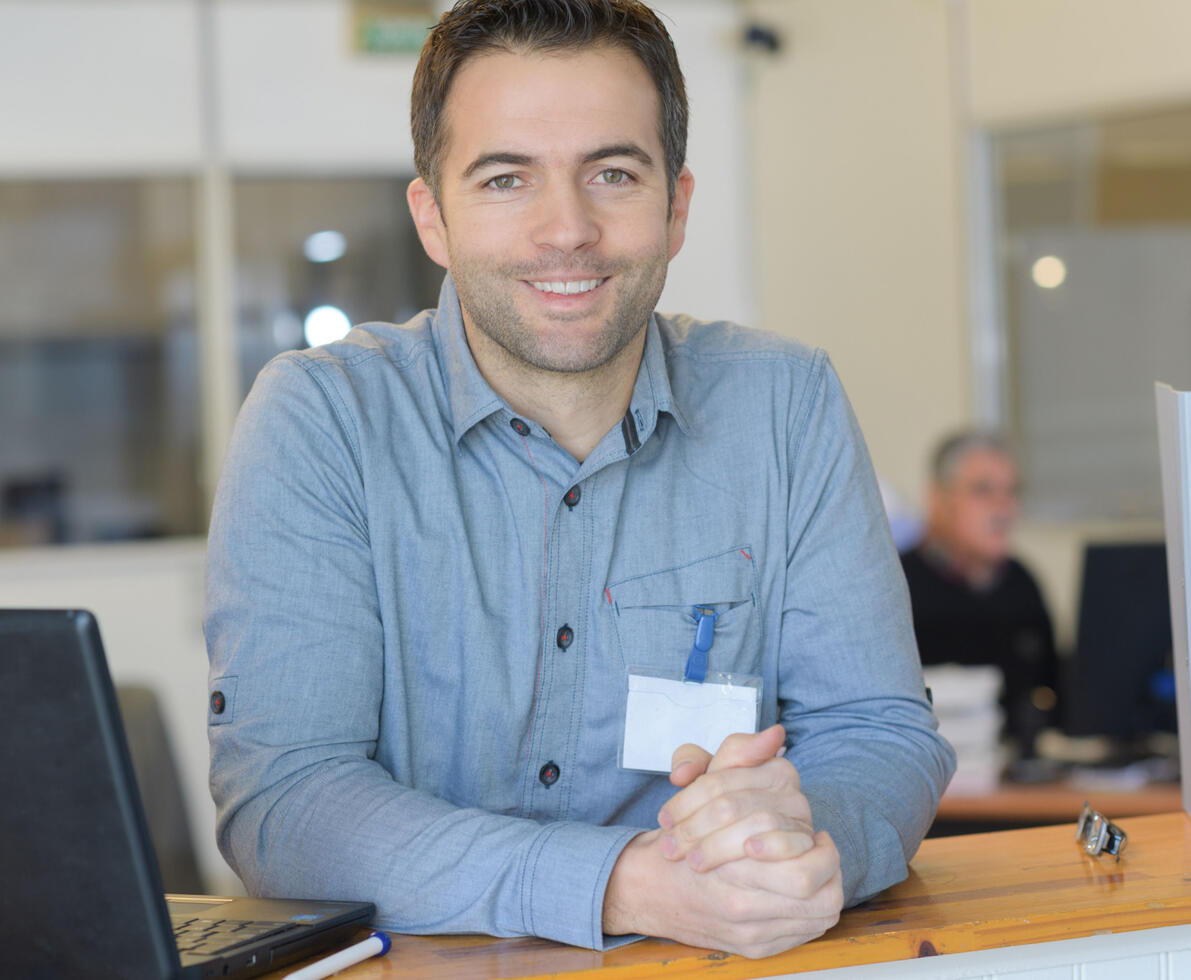 Young male smiling while sitting at an office desk