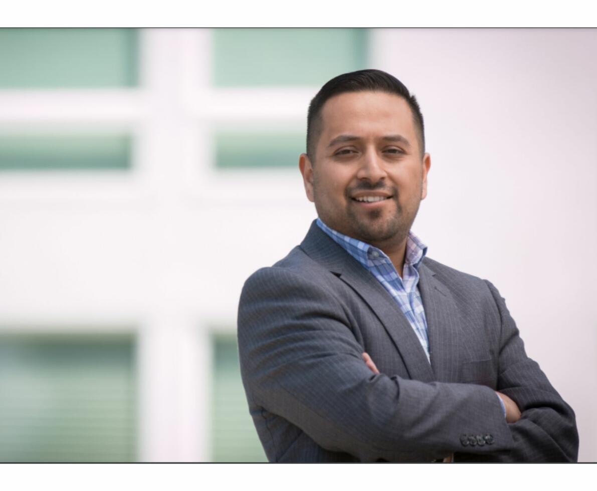 Hispanic man in a suit with arms crossed confidently