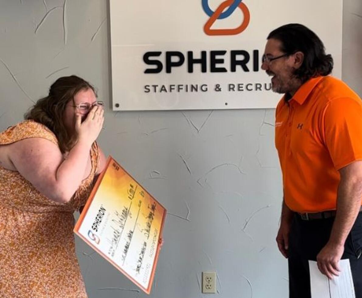 A girl on the left surprised and happy, standing next to a man on the right in an office setting