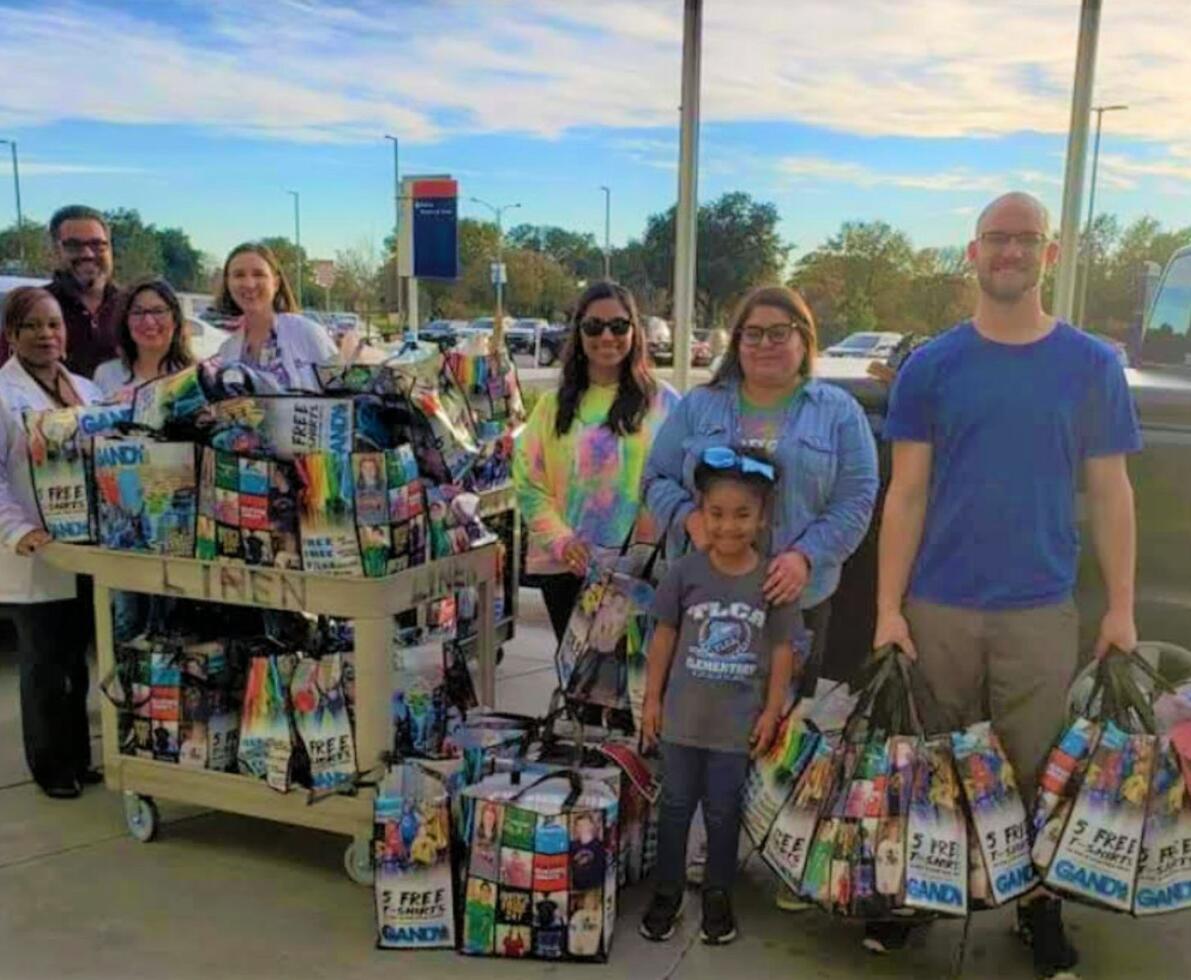 A group of people posing with donation bags in an outdoor parking lot
