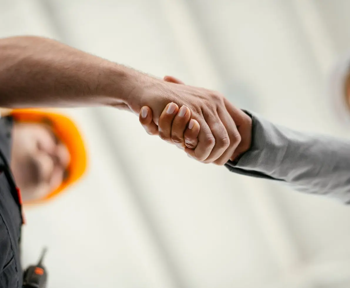 Close up of factory worker giving handshake to a engineer