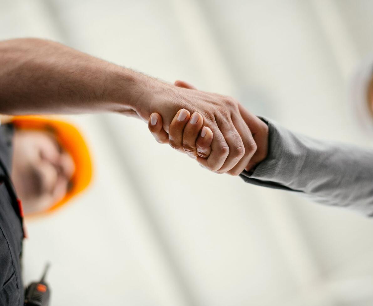 Close up of factory worker giving handshake to a engineer