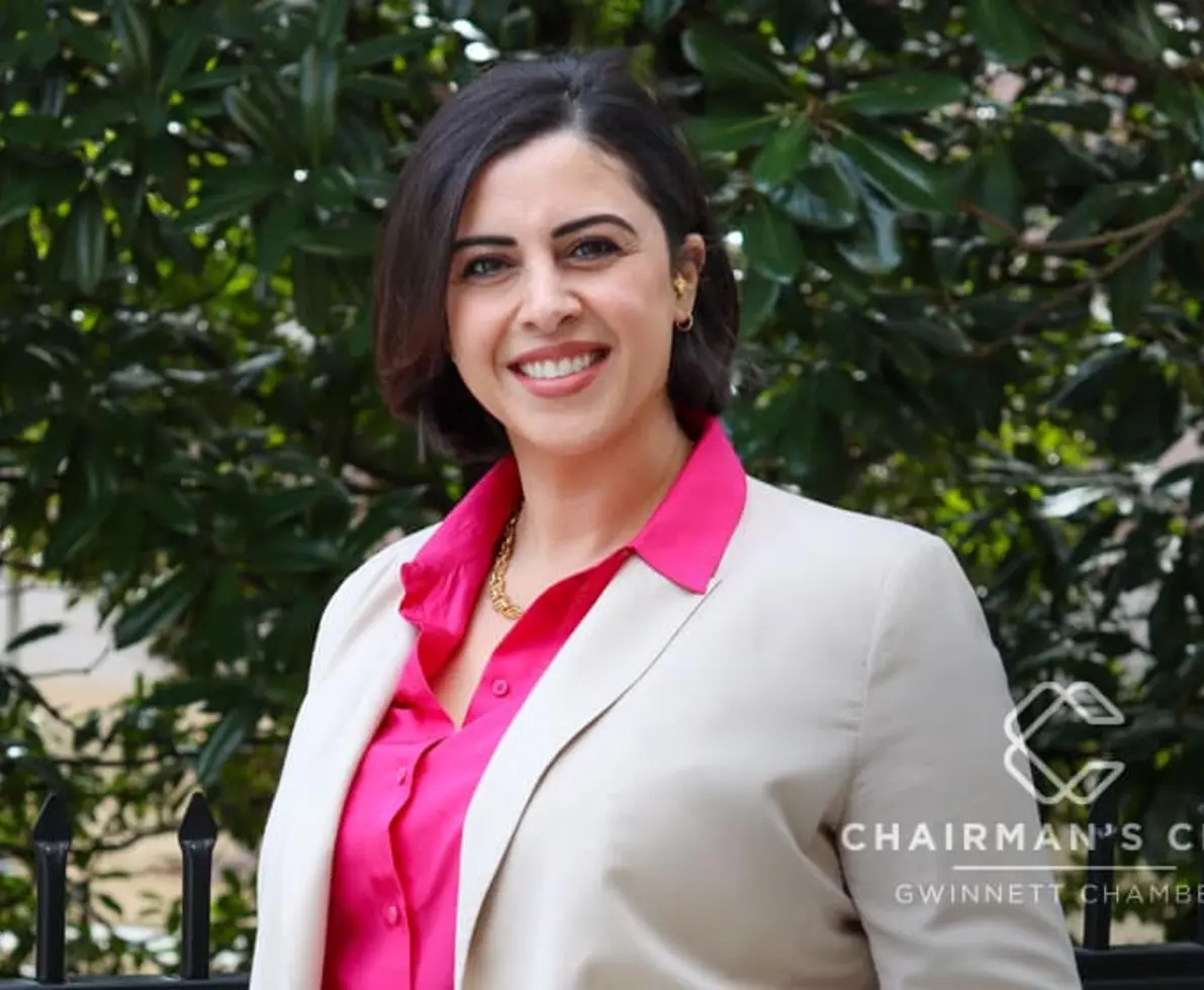 A photo of a woman in a business suit against a leafy backdrop