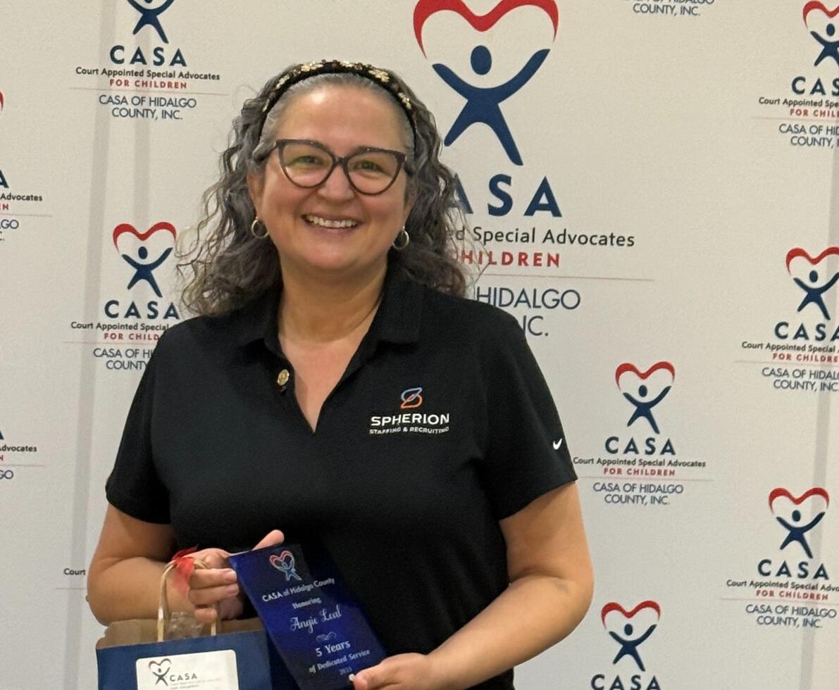 A woman smiling and holding a plaque
