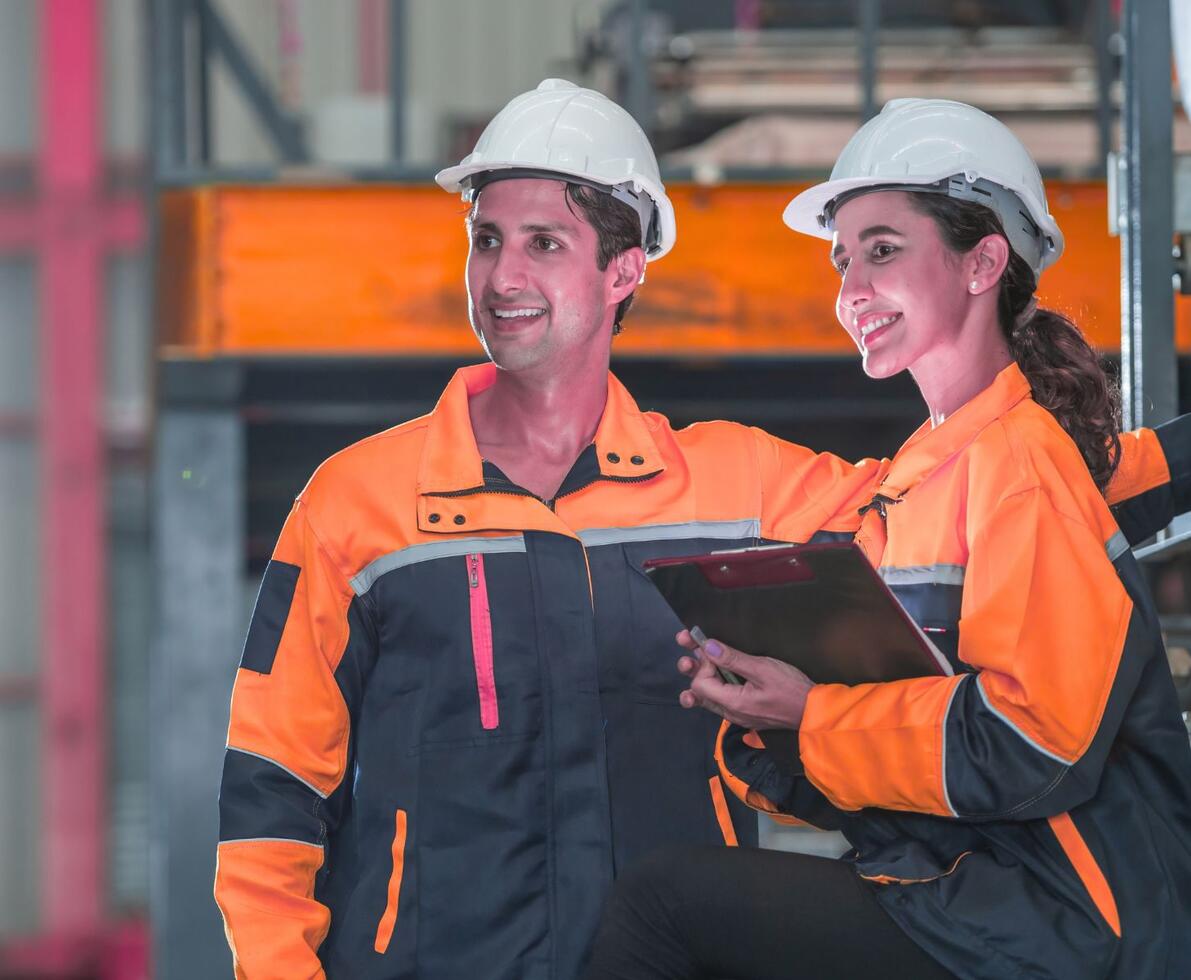 A man and woman in orange safety suits in a manufacturing plant