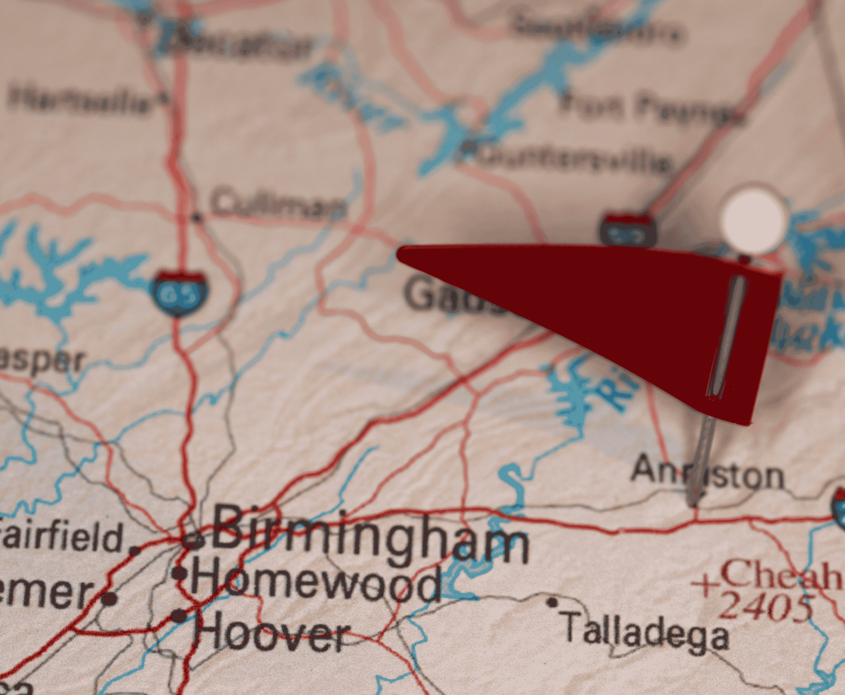Picture of a map of Alabama with a red flag pinned to Anniston